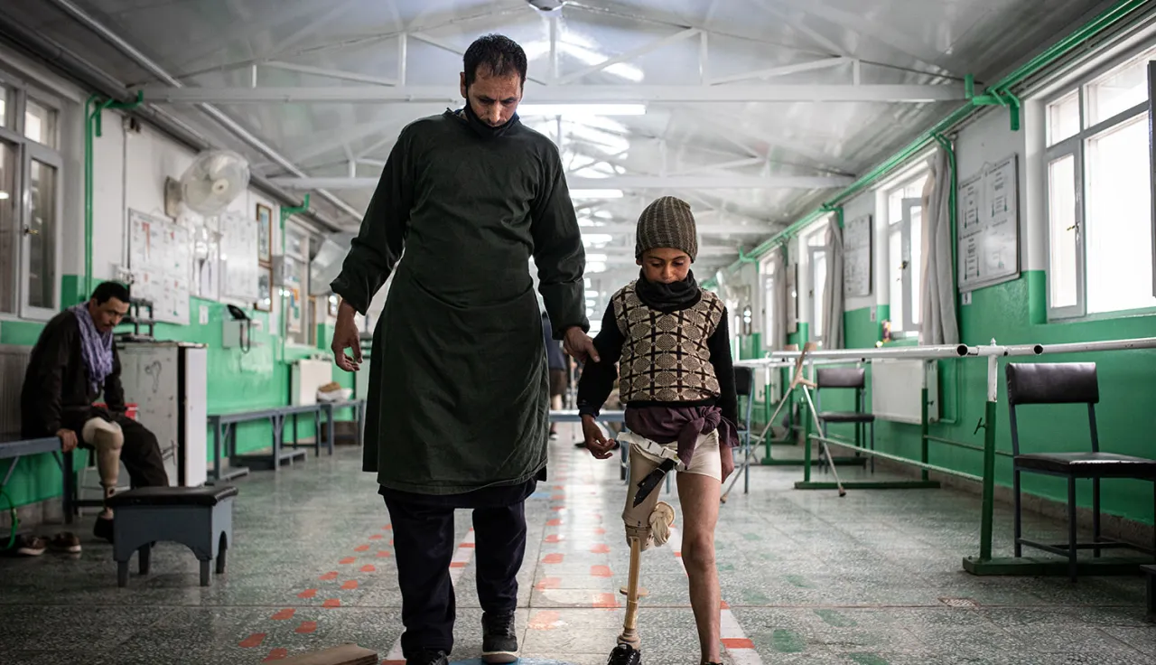 Man walking with boy with a prosthetic leg at rehabilitation center.