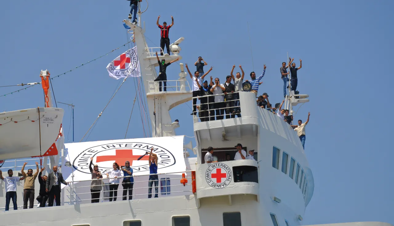 In Libya, during a family reunification operation, people on an ICRC-chartered boat wave to their loved ones as they wait to dock.