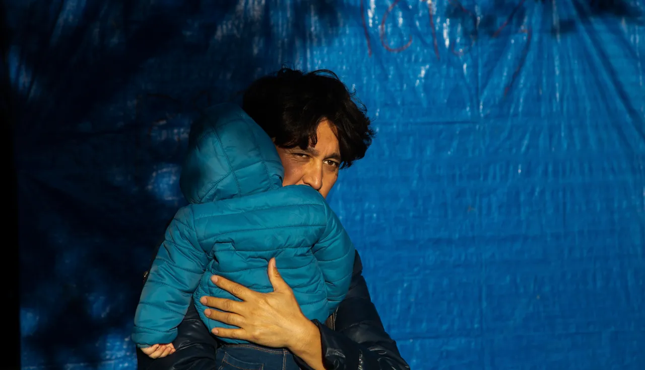 Afghan father and his child outside their makeshift tent in the Moria refugee camp.