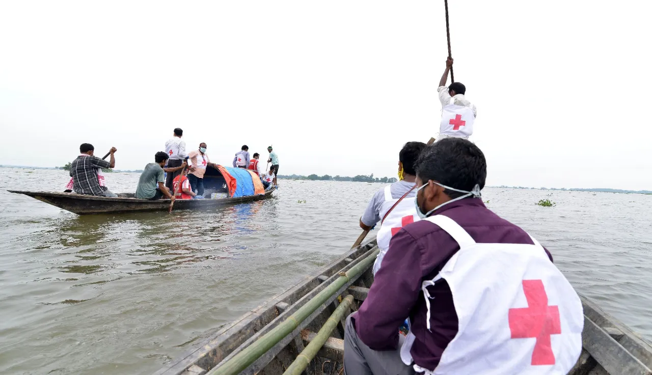 Volunteers of the Indian Red Cross Society travel in a boat to flood-affected districts in Assam, India, to distribute essential items.