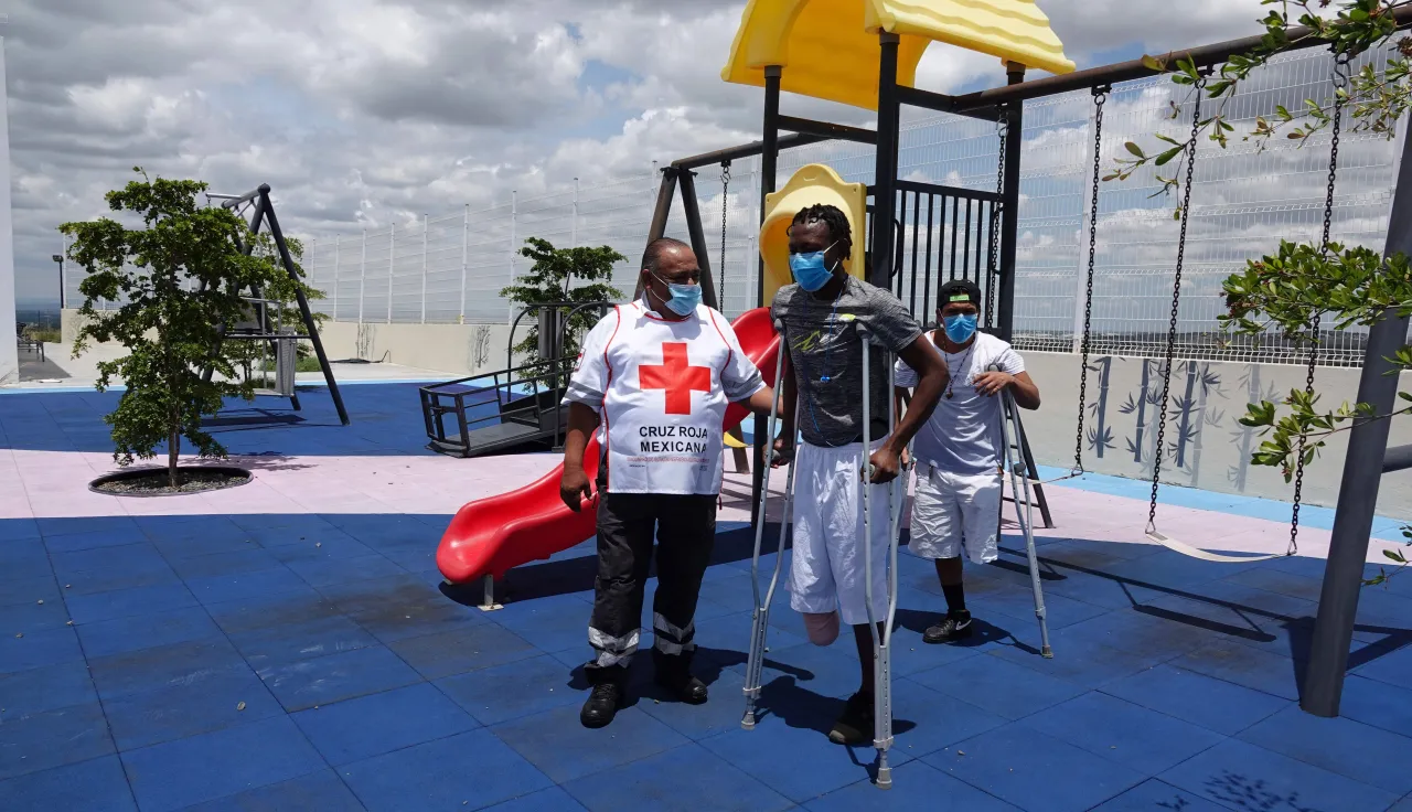 At an ICRC rehabilitation center in Guanajato, Mexico, a volunteer from the Mexican Red Cross assists two beneficiaries.