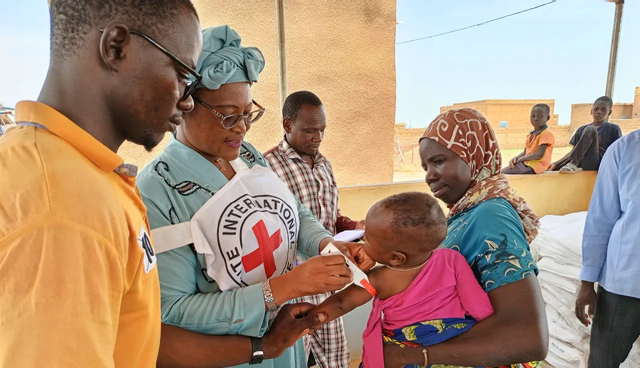 The ICRC distributes a corn-soya blend to an infant and his mother in Djibo, Burkina Faso.