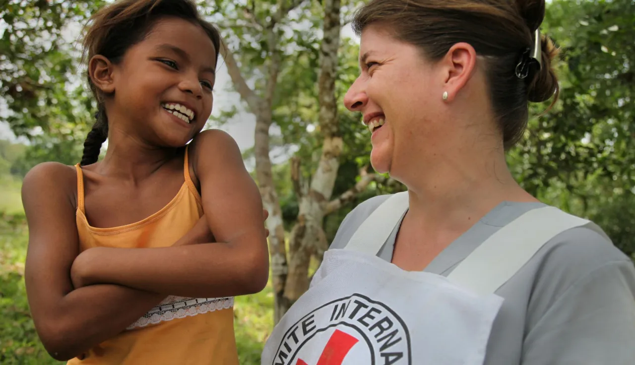 An ICRC delegate laughing with a girl from the community of La Ceiba.