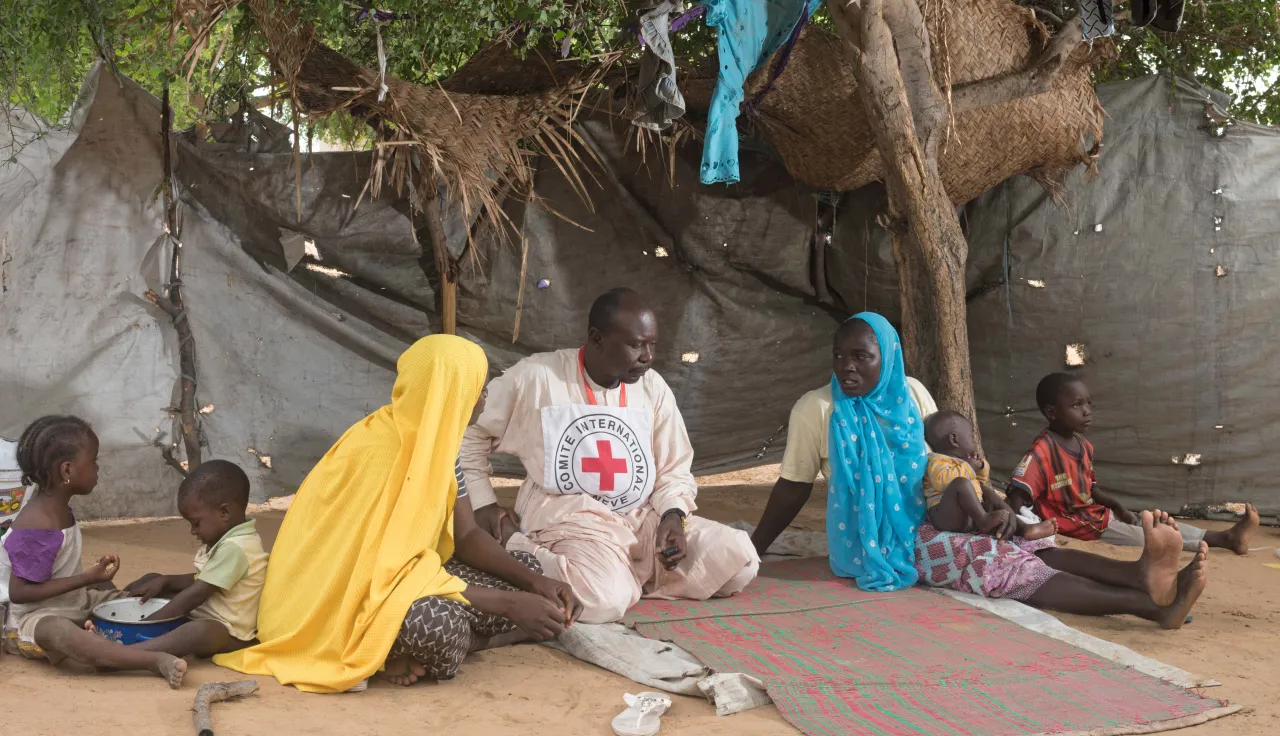 Two women who fled Nigeria and sought refuge in Chad speak with an ICRC employee about their living conditions in the refugee camp.
