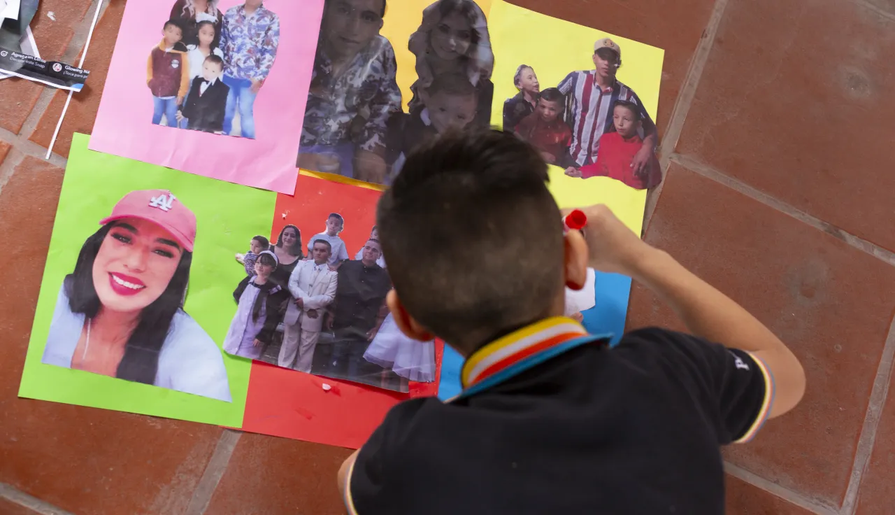 Un niño pega fotografías de sus seres queridos desaparecidos en hojas de colores. 