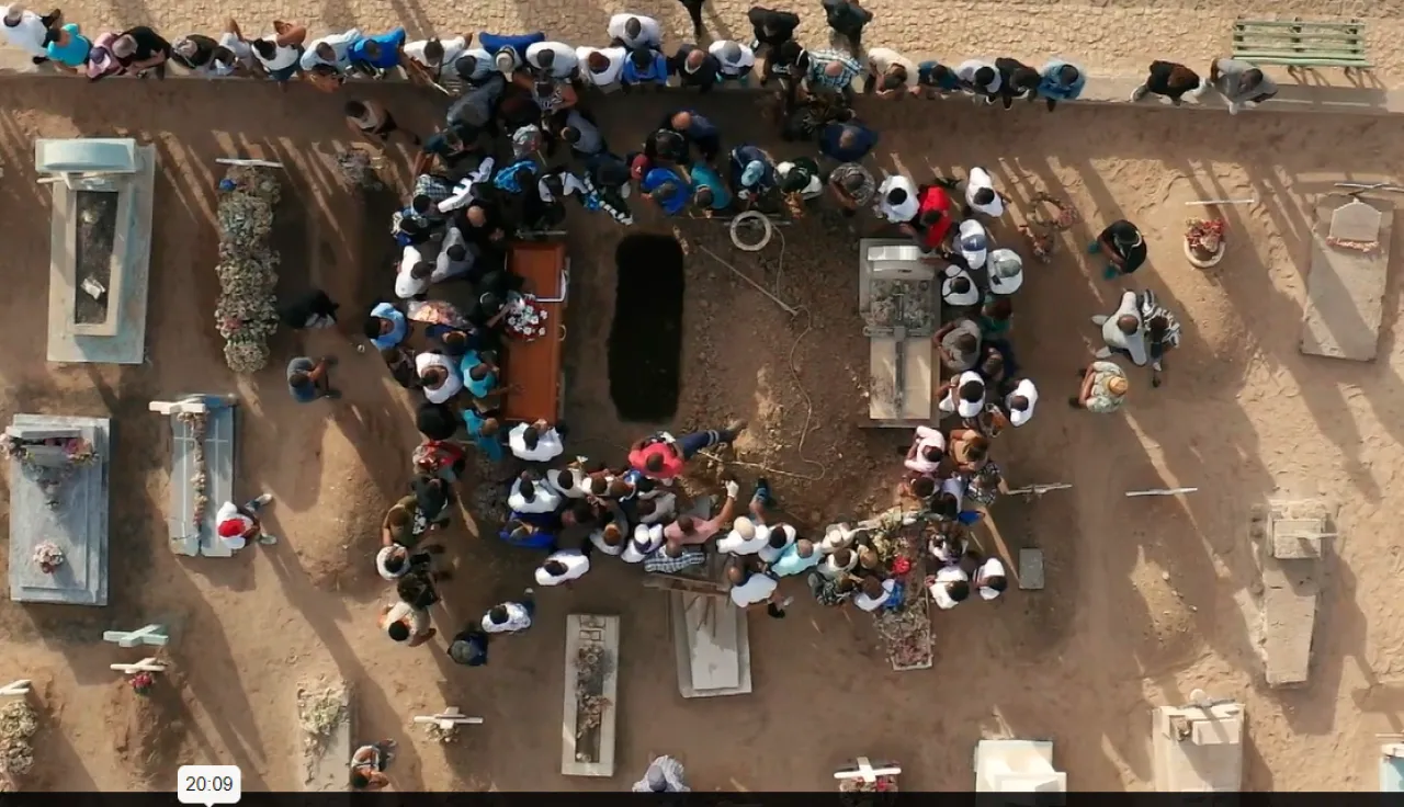 Group of people gathering around a coffin that will be buried 