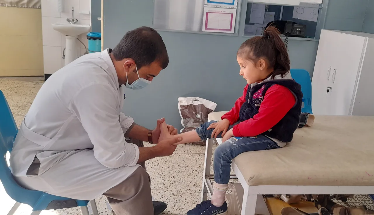 ICRC Doctor checking the ankle of a child seated on an examination table