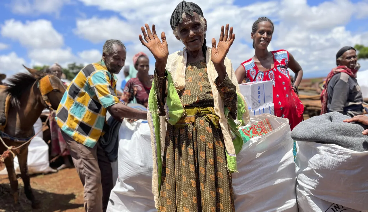 Woman at Ethipoian Red Cross Society distribution of food supplies and essential household items waves to the camera