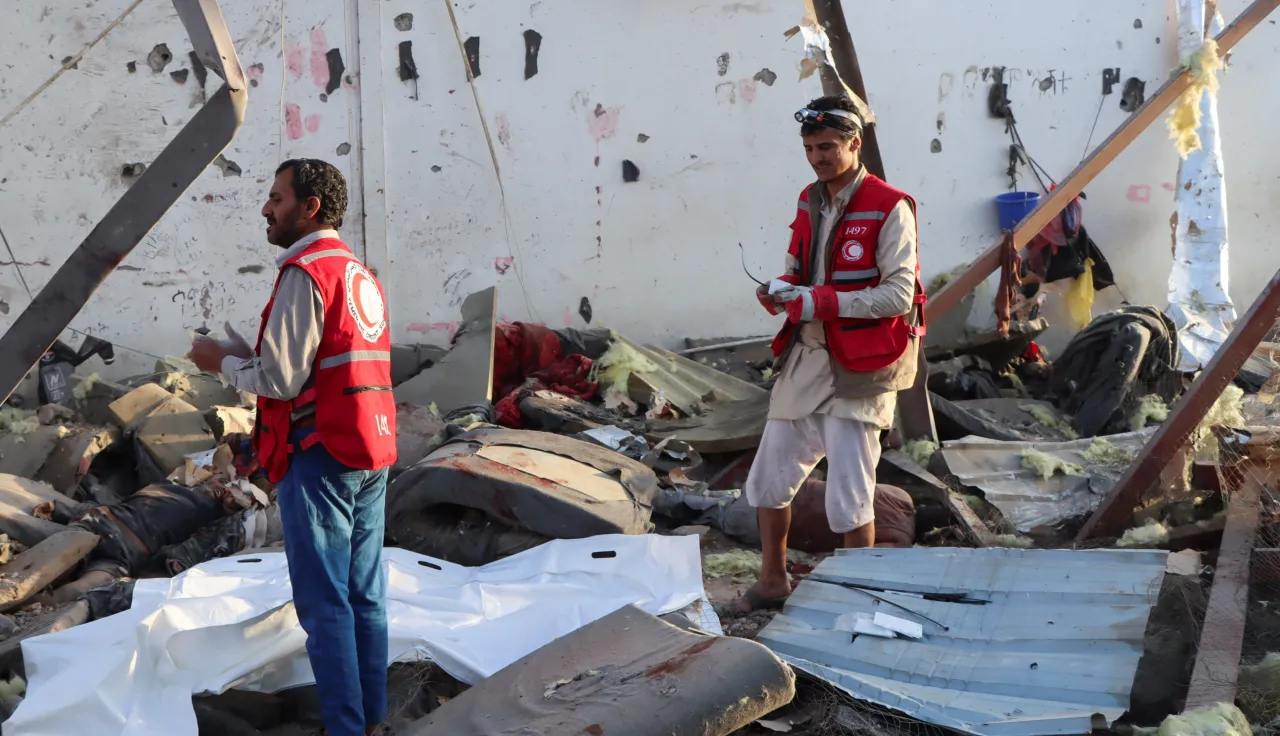 NR Yemen strikes Two Red Crescent workers stand amidst the wreckage caused by an explosion