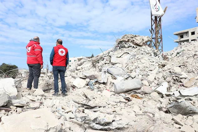 ICRC staff and Red Crescent staff standing on rubble