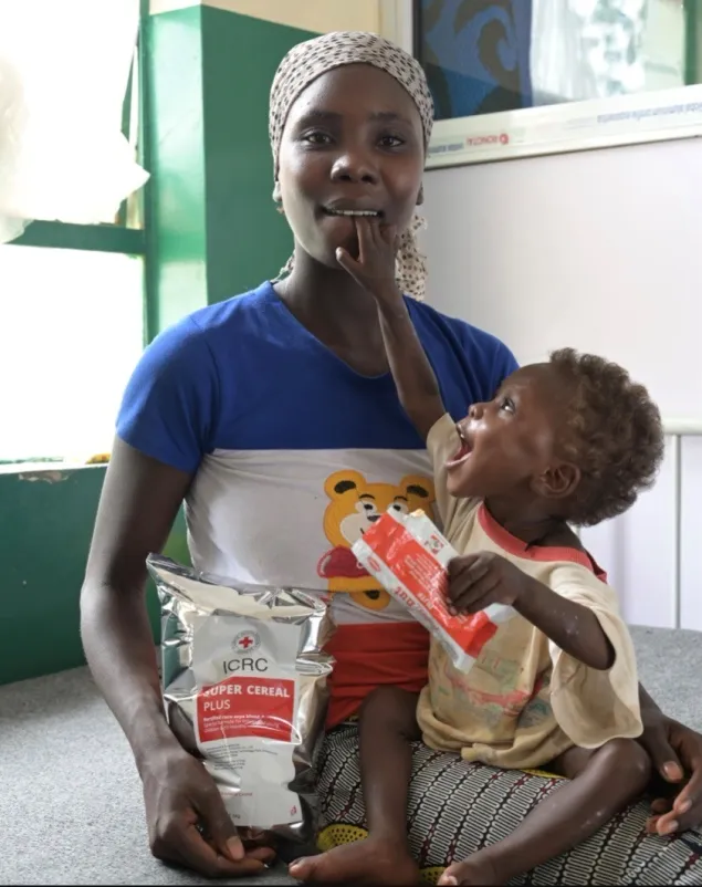 Sabina's mother holding the young child on her lap