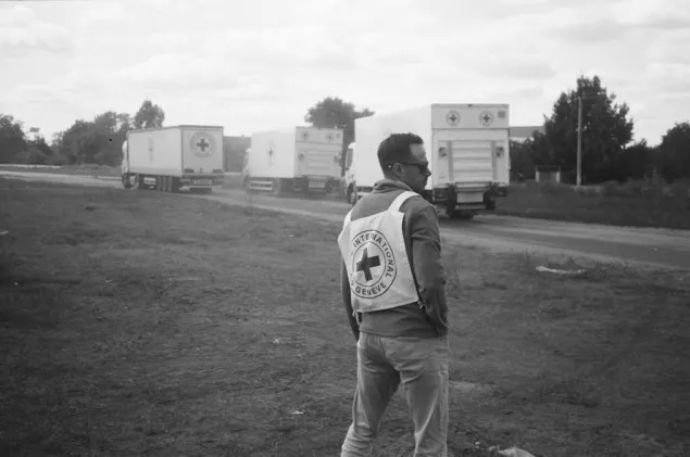 ICRC staff looks on as ICRC trucks passed on the road during a distribution of briquettes in the village of Pidlyman.