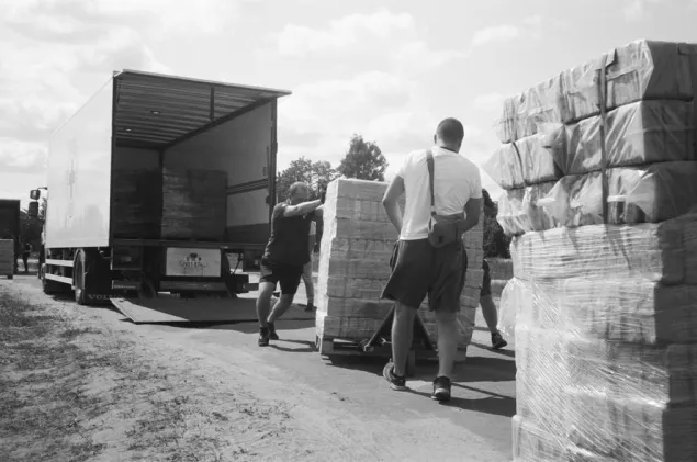 Men unload packages from an ICRC truck in the distribution of briquettes in the village of Pidlyman.