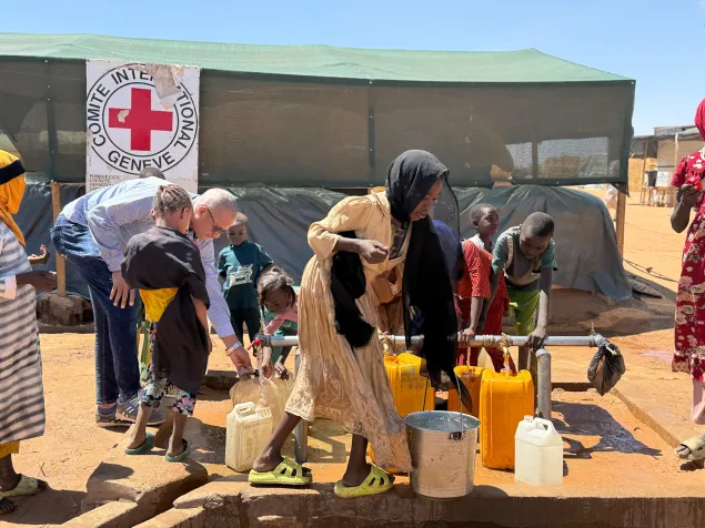 Aliou Sow, délégué eau et habitat avec des réfugiés soudanais devant un point d'eau CICR à Adré