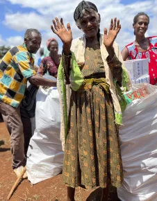 Woman at Ethipoian Red Cross Society distribution of food supplies and essential household items waves to the camera