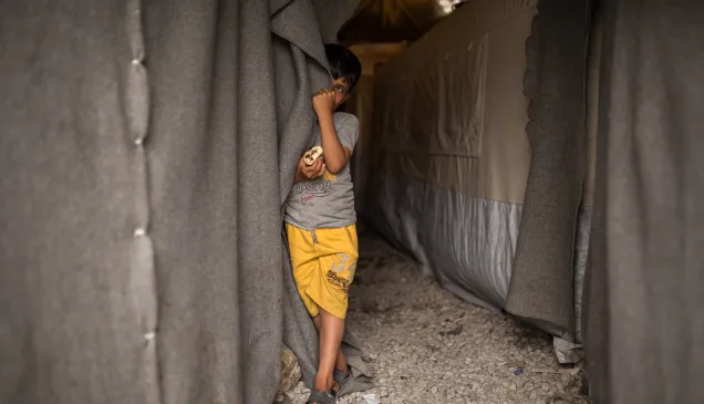 Child next to a tent in ICRC camp in Greece