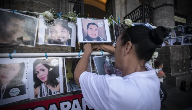 Una persona coloca una foto de su ser querido desaparecido.