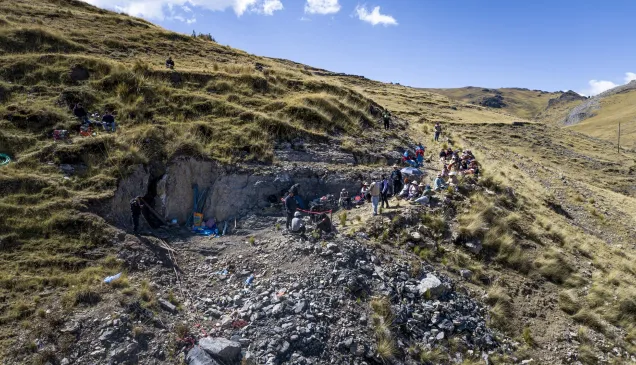 Toma aérea de una fosa en medio de una montaña, con personas presenciando detrás de un cordon de seguridad.