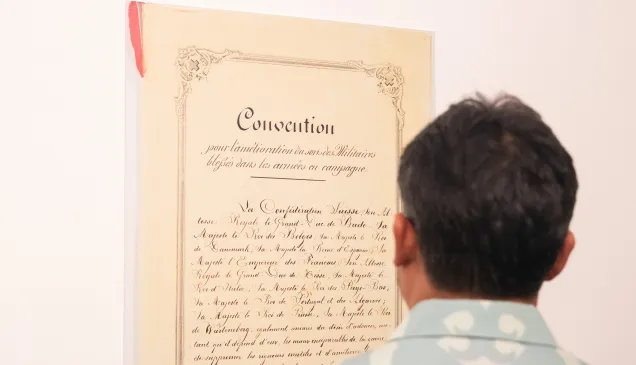 A visitor to the "Preserving humanity in war" photo exhibit views a copy of the 1864 Geneva Convention.