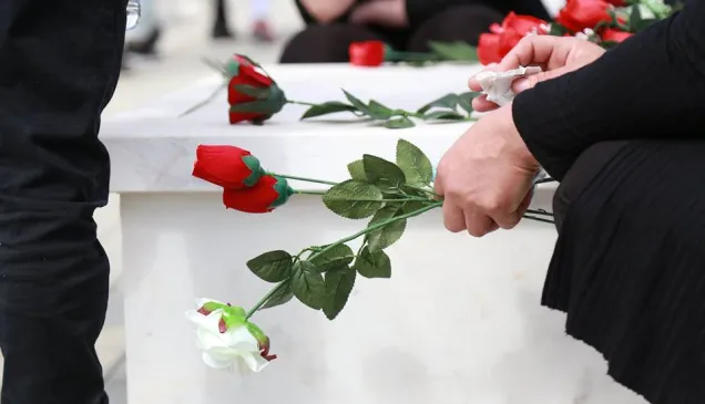 Red roses being placed at a memorial