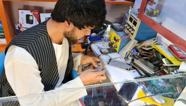 Baqir repairs a smartphone in his workshop in Mazar-i-Sharif