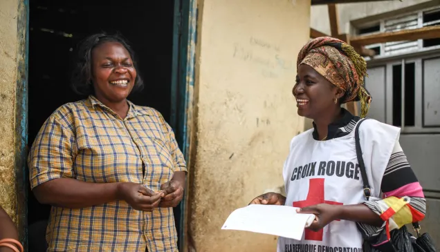 National Society Investment Alliance (NSIA) announces 2024 funding  ICRC delegate speaking to a smiling woman in a doorway
