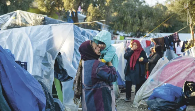 Lesbos, Moria, Olive Grove informal camp. A woman holds a baby in her arms. Lesbos, Moria, Olive Grove informal camp. A woman holds a baby in her arms.