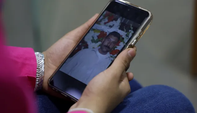 IDOD Syria Lana Noamaan Lana Noamaan holding a smartphone showing a picture of her father