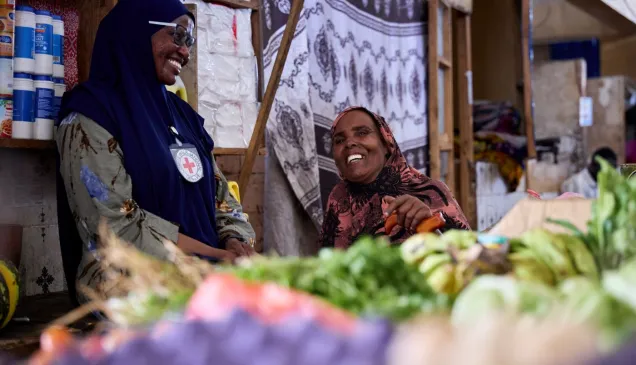 Una colaboradora del CICR y conversa y sonríe junto a una mujer. 