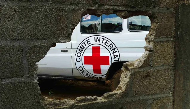 Emblem on the side of ICRC vehicle seen through a hole in a brick wall