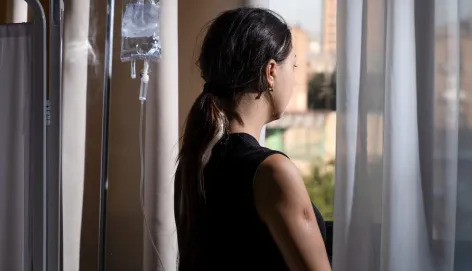 Tatev Aristakesyan looks out of a window in a hospital and has her back to the camera.