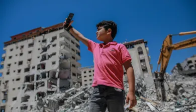  A little boy takes a picture with his smartphone in the middle of rubble of war. As a resident of Gaza, he had to go through numerous traumatic experiences of war. AL-MASHHARAWI, Yousef Al-Mashharawi/ICRC