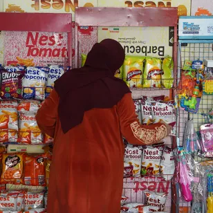 Woman with her back to the camera, shelves of food in front of her