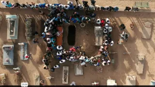 Group of people gathering around a coffin that will be buried 