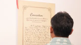 A visitor to the "Preserving humanity in war" photo exhibit views a copy of the 1864 Geneva Convention.