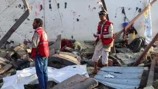 NR Yemen strikes Two Red Crescent workers stand amidst the wreckage caused by an explosion