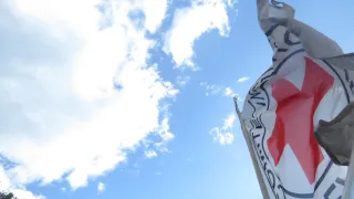 Bandera del CICR ondeando con el cielo y las nubes en el fondo