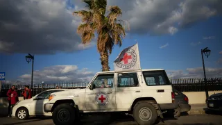 An ICRC vehicle displaying the Red Cross emblem and flag is parked along a coastal road in Lebanon during humanitarian operations amid escalating hostilities.