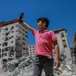  A little boy takes a picture with his smartphone in the middle of rubble of war. As a resident of Gaza, he had to go through numerous traumatic experiences of war. AL-MASHHARAWI, Yousef Al-Mashharawi/ICRC