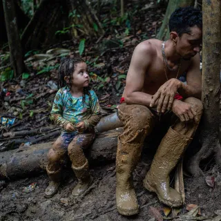 Photograph of child and man sitting on a fallen tree branch