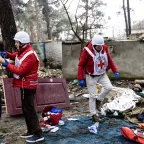 Funcionários do CICV conversam com pessoa afetada por conflito na Ucrânia em meio a escombros.