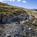 Toma aérea de una fosa en medio de una montaña, con personas presenciando detrás de un cordon de seguridad.