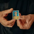 A woman in iraq holds a passport sized photograph of a missing relative