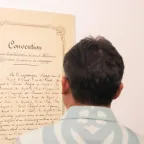 A visitor to the "Preserving humanity in war" photo exhibit views a copy of the 1864 Geneva Convention.