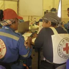 ICRC and Red Cross delegates sitting with their backs to the camera wearing the emblem on their clothing