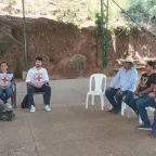 Seis personas, entre ellas dos con el emblema del CICR, sentadas en sillas en un espacio abierto.