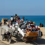 Gaza-City-September-2025-CREDIT-REUTERS-CONNECT_GAZA.JPG A crowded truck loaded with people and belongings drives along a coastal road, as others walk or travel on carts beside the sea.