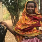 A woman carrying a child fills up a garden sprinkler in her other hand. ICRC A woman carrying a child fills up a garden sprinkler in her other hand.