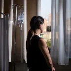 Tatev Aristakesyan looks out of a window in a hospital and has her back to the camera.