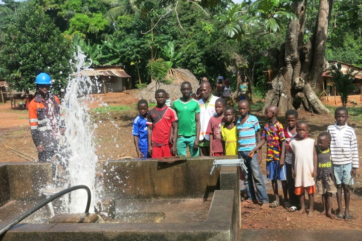 Des enfants du village regardent avec fascination le spectacle de l’eau qui jaillit du puit.